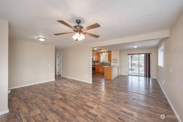 unfurnished living room with a textured ceiling, dark hardwood / wood-style flooring, ceiling fan, and sink