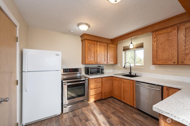 kitchen with appliances with stainless steel finishes, a textured ceiling, dark hardwood / wood-style floors, and sink