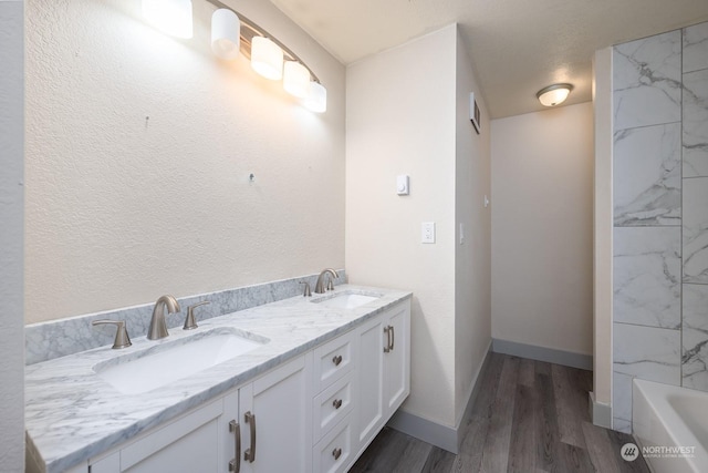 bathroom featuring hardwood / wood-style flooring, vanity, a tub to relax in, and a textured ceiling