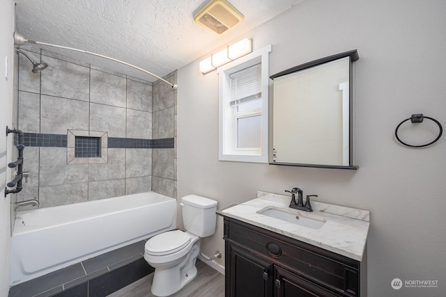 full bathroom with tiled shower / bath combo, a textured ceiling, toilet, vanity, and hardwood / wood-style flooring