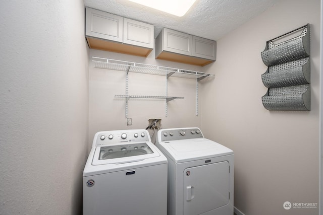 laundry area with cabinets, separate washer and dryer, and a textured ceiling