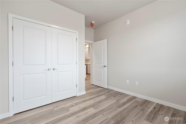 unfurnished bedroom featuring light hardwood / wood-style flooring and a closet