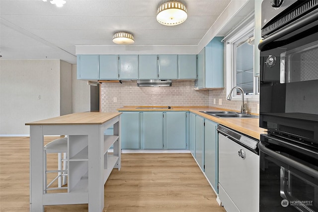 kitchen featuring white dishwasher, sink, blue cabinetry, tasteful backsplash, and light hardwood / wood-style floors