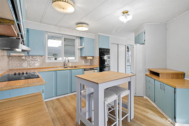 kitchen featuring black appliances, blue cabinets, sink, and light hardwood / wood-style flooring