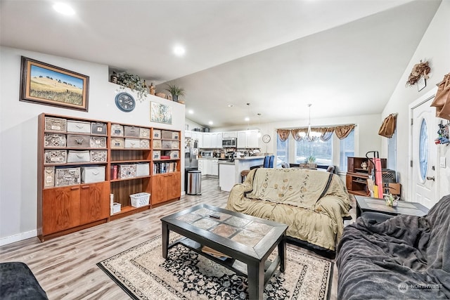 living room with lofted ceiling, light hardwood / wood-style floors, and a chandelier