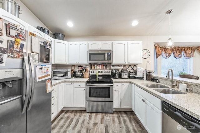 kitchen with stainless steel appliances, sink, white cabinets, and decorative light fixtures