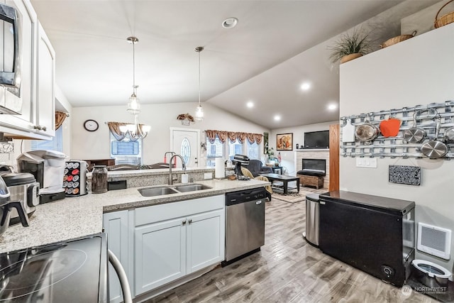 kitchen featuring sink, vaulted ceiling, hanging light fixtures, stainless steel appliances, and white cabinets