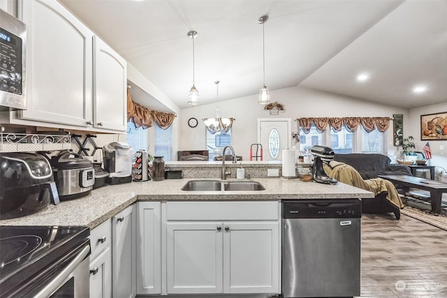 kitchen with vaulted ceiling, white cabinetry, sink, hanging light fixtures, and stainless steel appliances