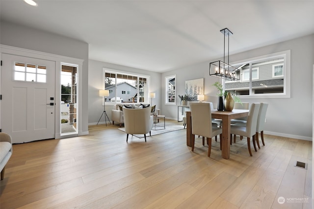 dining space featuring light wood-type flooring and a notable chandelier