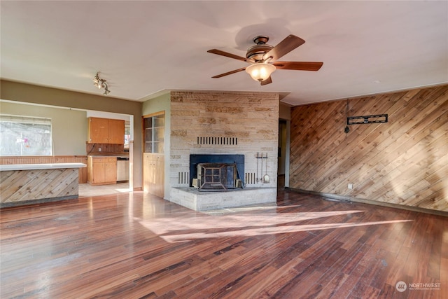 unfurnished living room featuring ceiling fan, wooden walls, and hardwood / wood-style floors