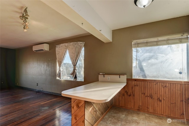 kitchen with kitchen peninsula, rail lighting, a wall mounted AC, and wood walls