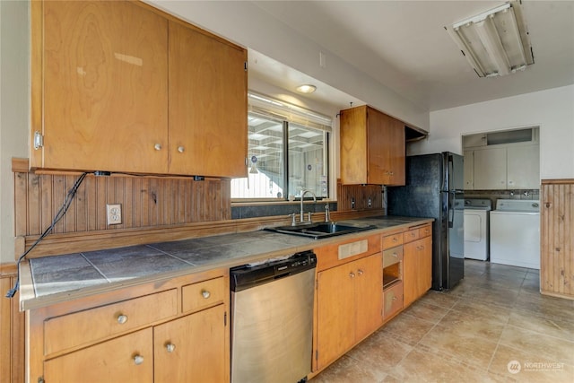 kitchen featuring sink, black fridge, tile countertops, stainless steel dishwasher, and washer and clothes dryer