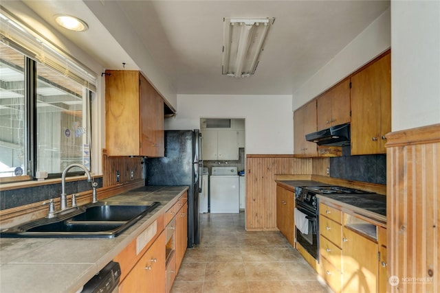 kitchen featuring washing machine and clothes dryer, tile countertops, sink, and black appliances