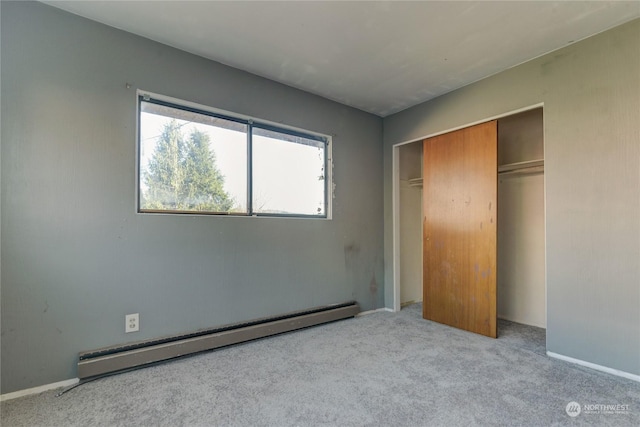 unfurnished bedroom featuring a baseboard heating unit, light colored carpet, and a closet