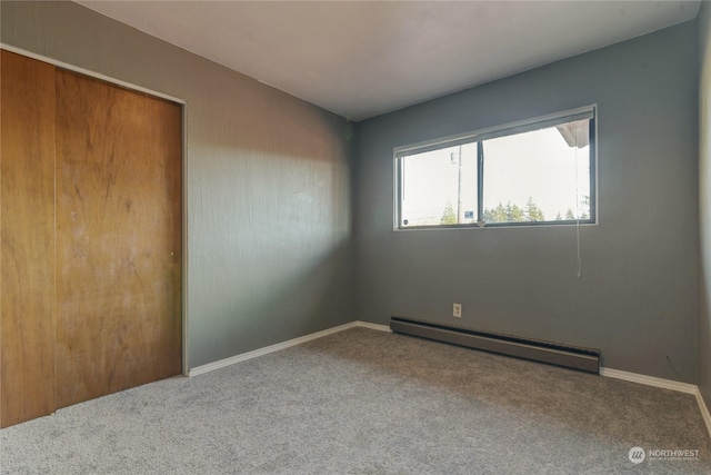 unfurnished bedroom with baseboard heating, carpet floors, and a closet