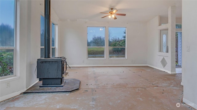 unfurnished living room featuring a wood stove and ceiling fan