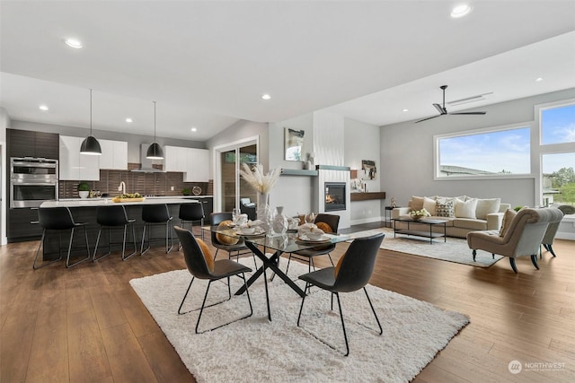 dining space with vaulted ceiling, ceiling fan, and dark wood-type flooring