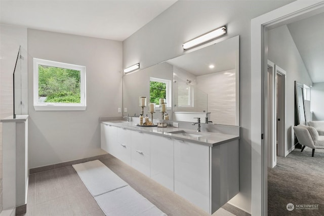 bathroom with plenty of natural light, vanity, vaulted ceiling, and tiled shower