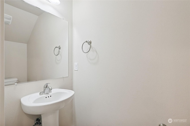 bathroom with sink, vaulted ceiling, and toilet