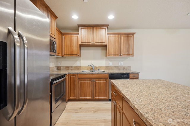 kitchen featuring light stone countertops, sink, stainless steel appliances, and light hardwood / wood-style flooring