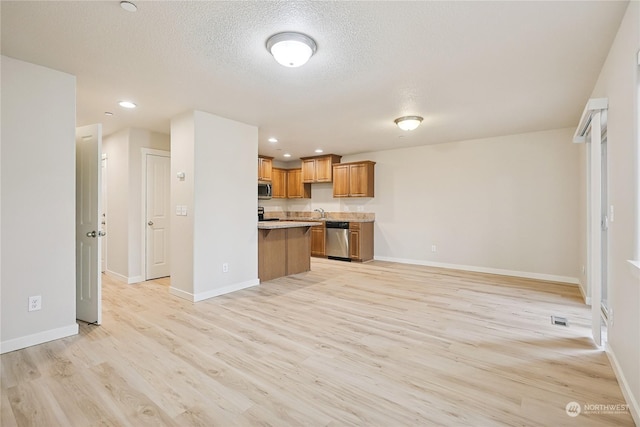 kitchen featuring light hardwood / wood-style floors, a textured ceiling, and appliances with stainless steel finishes