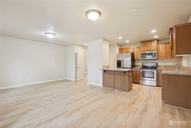 kitchen featuring a textured ceiling, appliances with stainless steel finishes, and light hardwood / wood-style flooring