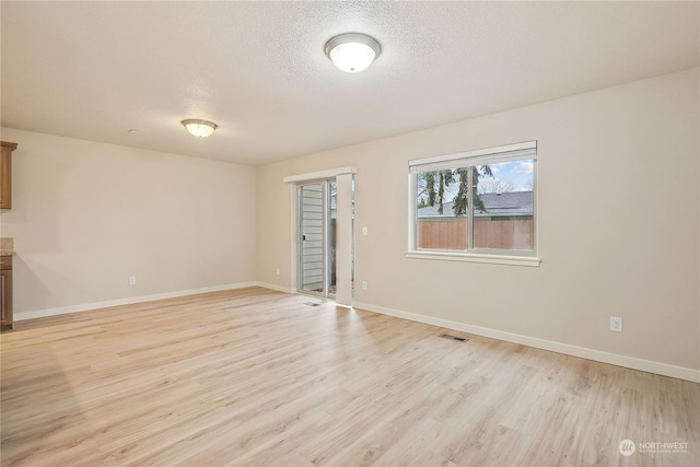 spare room featuring a textured ceiling and light hardwood / wood-style flooring