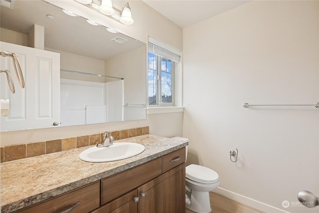 bathroom with vanity, toilet, and a shower