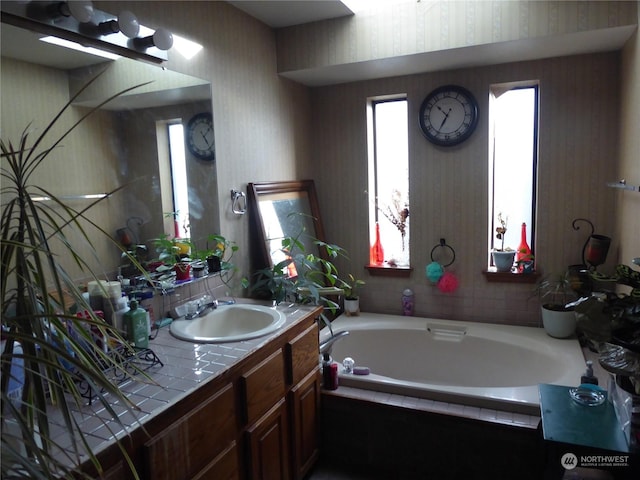 bathroom featuring vanity and tiled bath