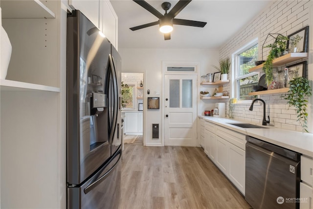 kitchen with sink, white cabinets, light hardwood / wood-style flooring, and appliances with stainless steel finishes