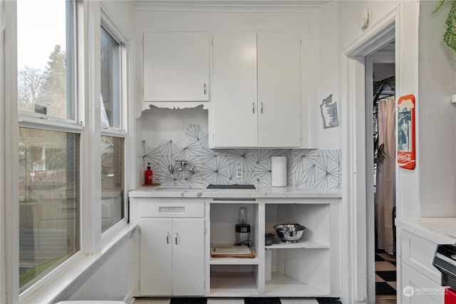 kitchen with decorative backsplash, white cabinets, and light stone countertops