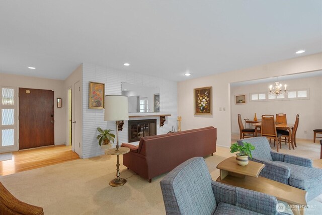 living room with recessed lighting, an inviting chandelier, a wealth of natural light, and a fireplace