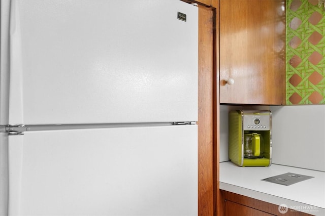 room details featuring light countertops, brown cabinets, and freestanding refrigerator