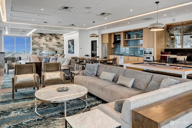 living room with pool table, a raised ceiling, and sink