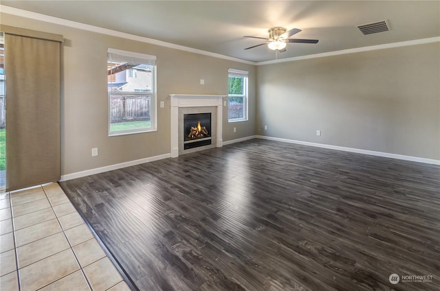 unfurnished living room with ornamental molding, light wood-type flooring, a healthy amount of sunlight, and a tiled fireplace