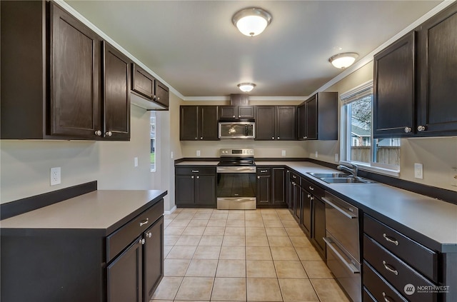 kitchen with light tile patterned flooring, dark brown cabinets, stainless steel appliances, and sink