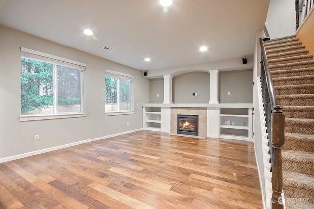 unfurnished living room featuring a tile fireplace and light hardwood / wood-style flooring