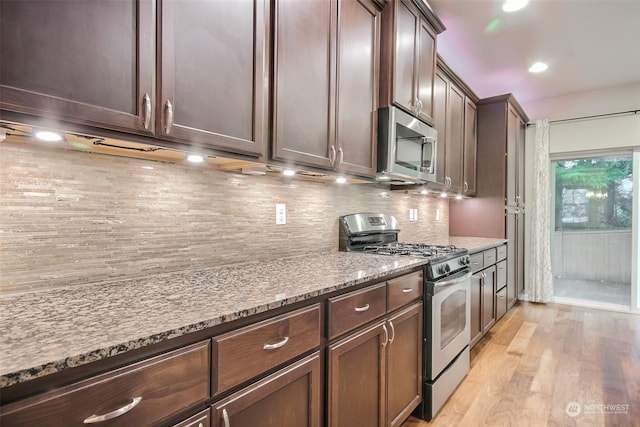 kitchen featuring backsplash, light hardwood / wood-style flooring, appliances with stainless steel finishes, dark brown cabinets, and light stone counters