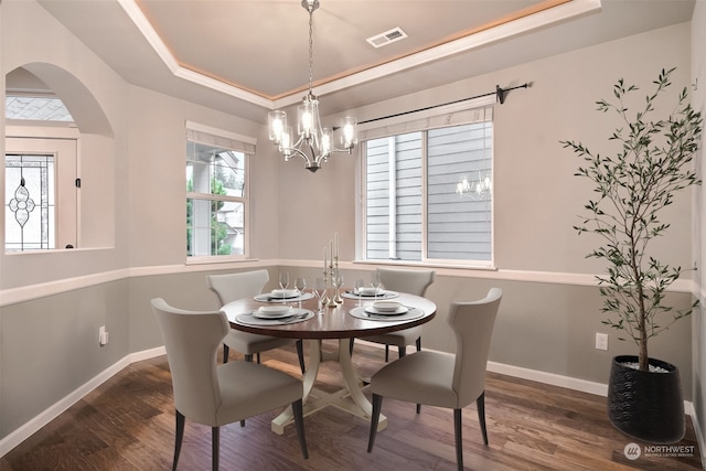 dining room with a raised ceiling, dark wood-type flooring, and a chandelier