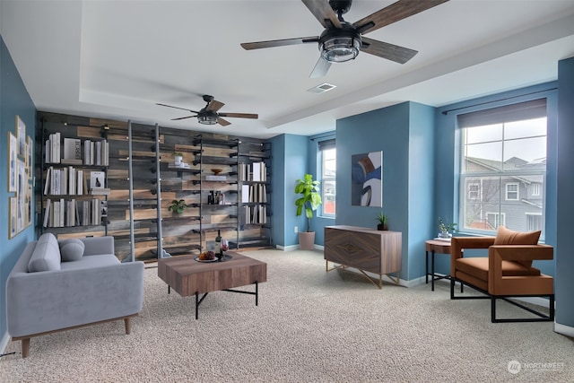 sitting room featuring carpet, ceiling fan, and a tray ceiling