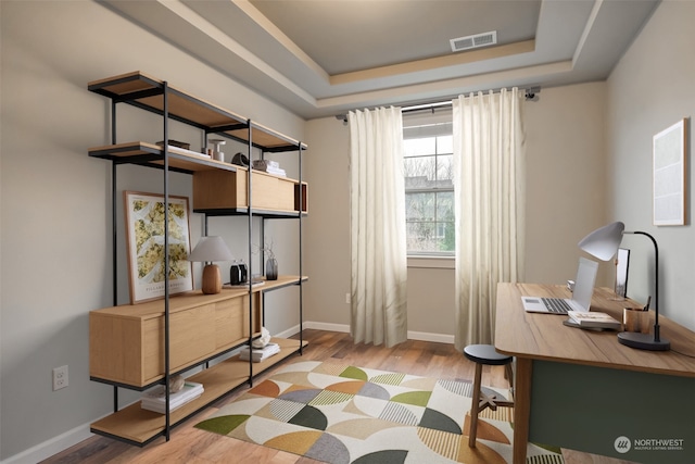 office space featuring light hardwood / wood-style floors and a tray ceiling