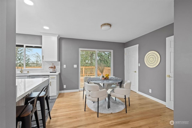 dining space with plenty of natural light, sink, and light hardwood / wood-style flooring