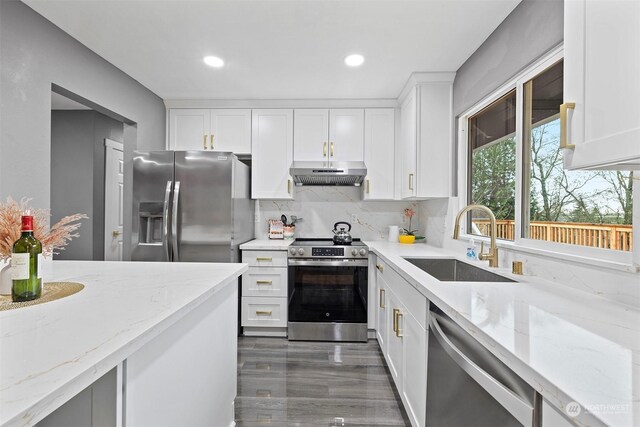 kitchen with white cabinets, stainless steel appliances, light stone counters, and sink