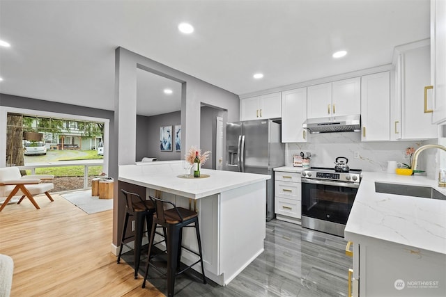 kitchen featuring a breakfast bar, sink, a kitchen island, white cabinetry, and stainless steel appliances