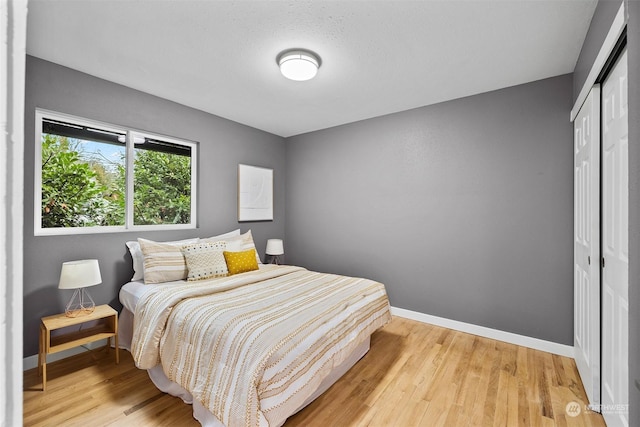 bedroom with light wood-type flooring, a textured ceiling, and a closet