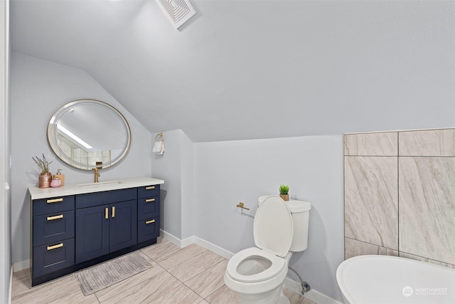 bathroom with toilet, vanity, and vaulted ceiling