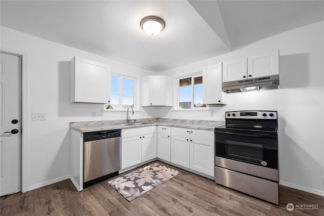 kitchen featuring light stone countertops, sink, hardwood / wood-style floors, white cabinets, and appliances with stainless steel finishes