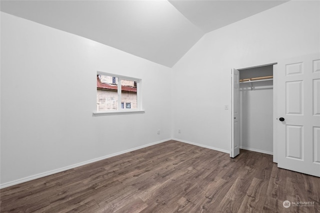 unfurnished bedroom with dark hardwood / wood-style flooring, lofted ceiling, and a closet