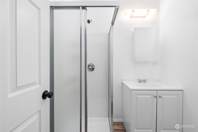 bathroom featuring hardwood / wood-style flooring, vanity, and walk in shower