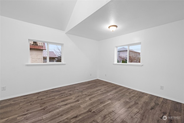 unfurnished room with a healthy amount of sunlight, dark hardwood / wood-style flooring, and lofted ceiling